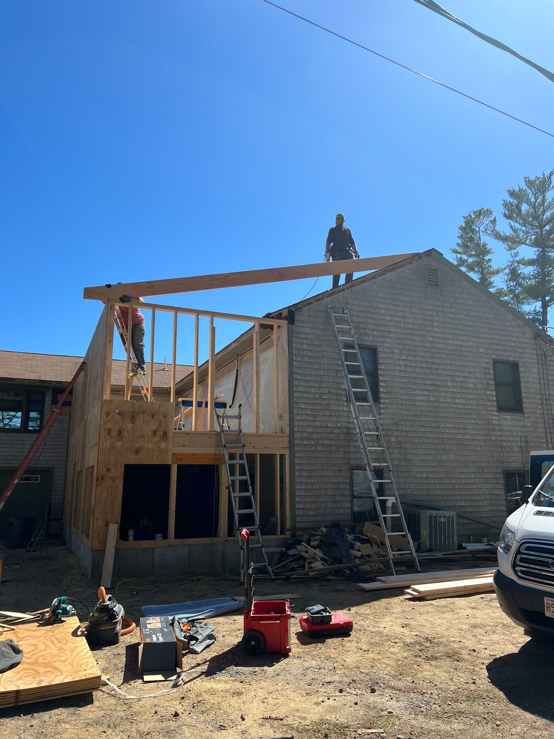 A man is standing on the roof of a house under construction.