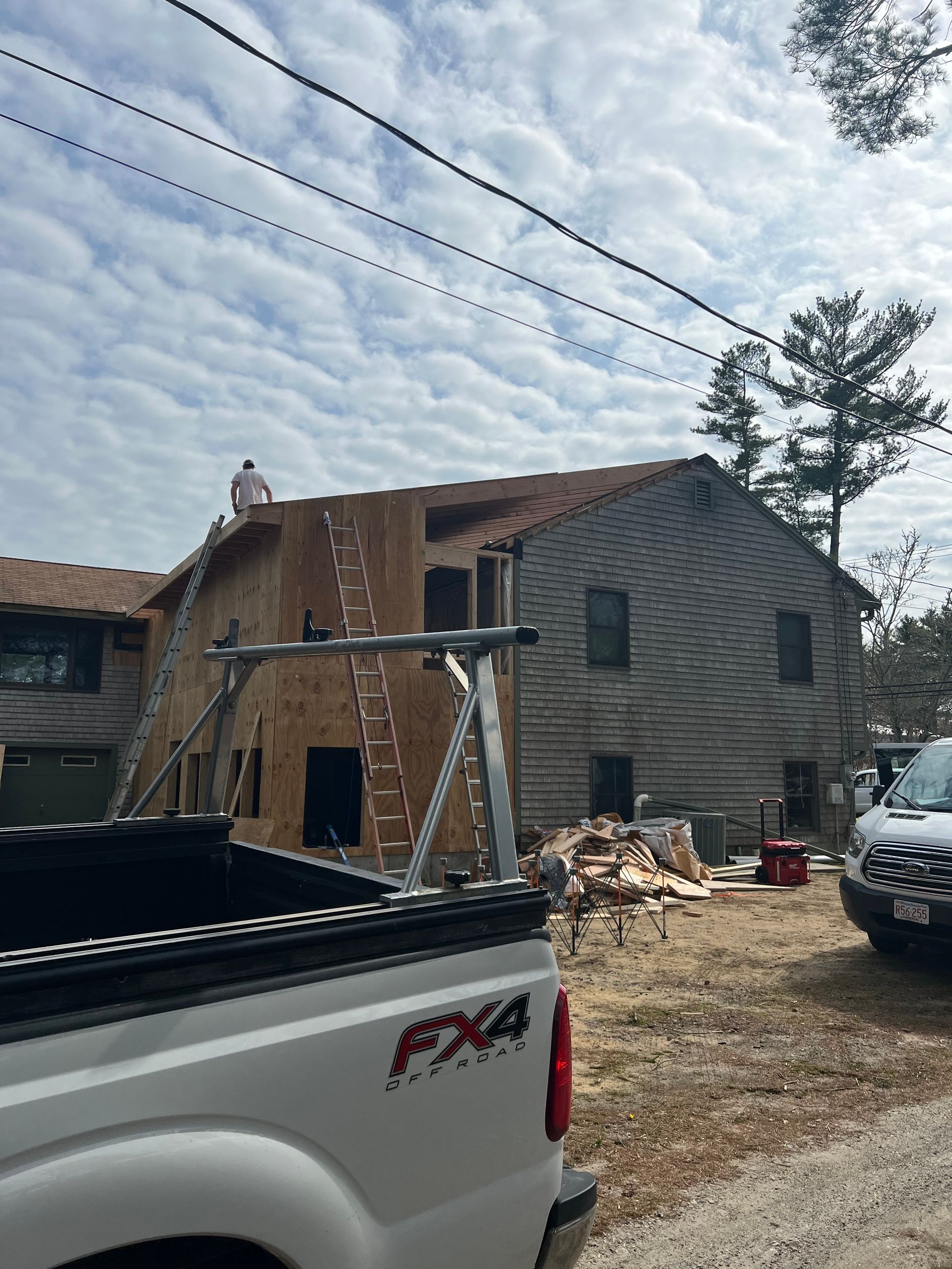 A white truck is parked in front of a house under construction.