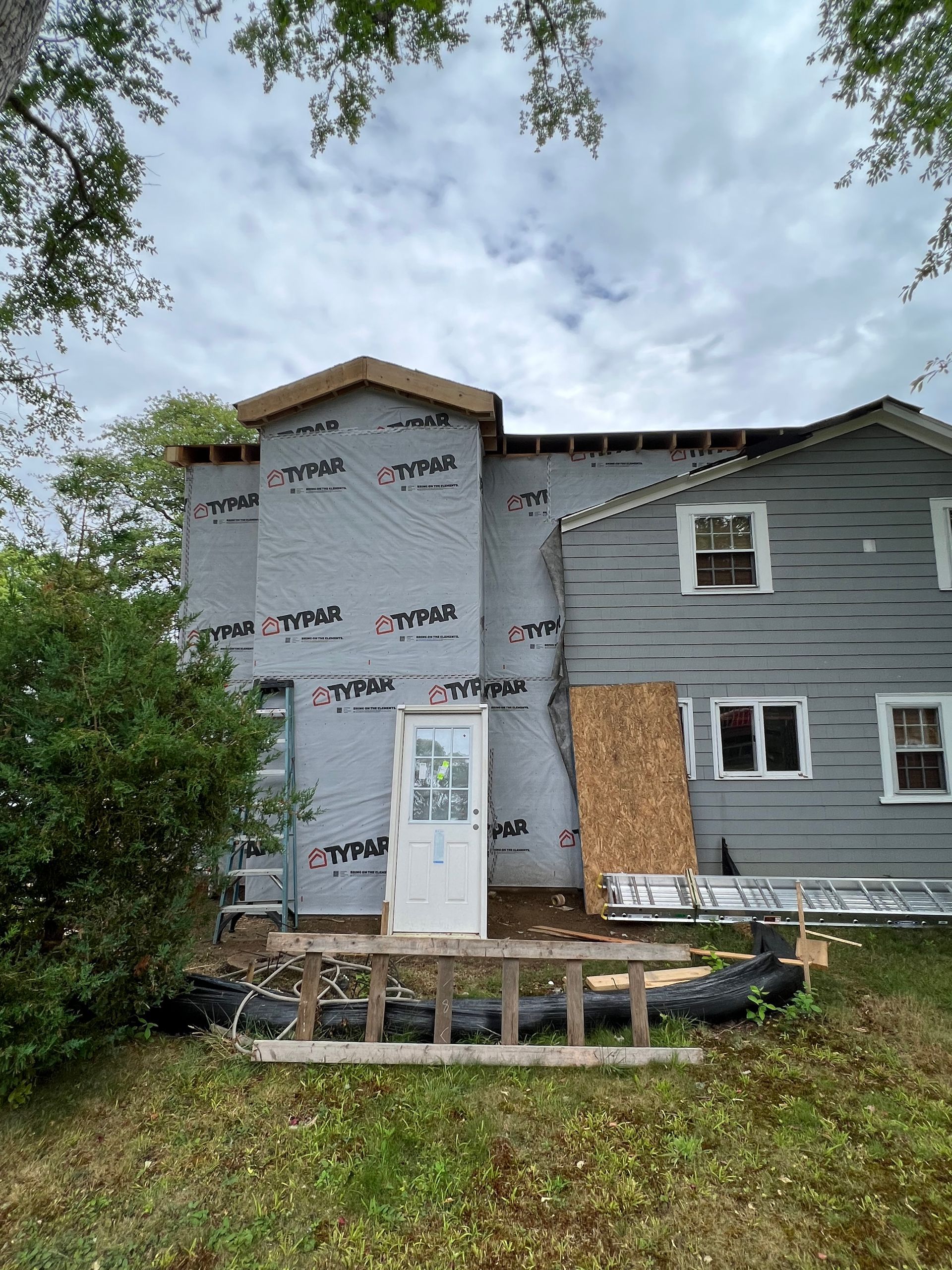 A gray house with a white door is being remodeled.