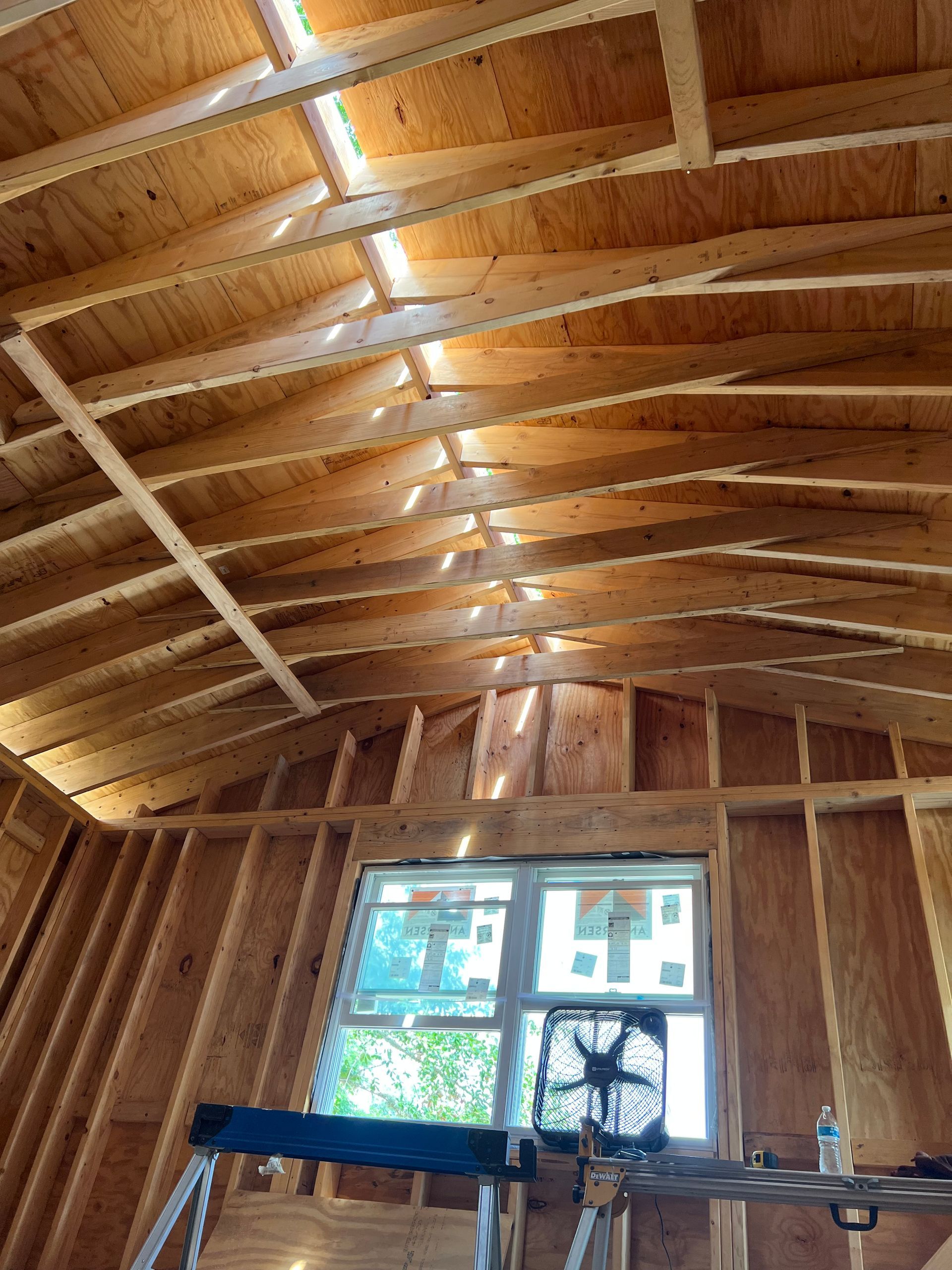 The inside of a building under construction with a window and a fan.