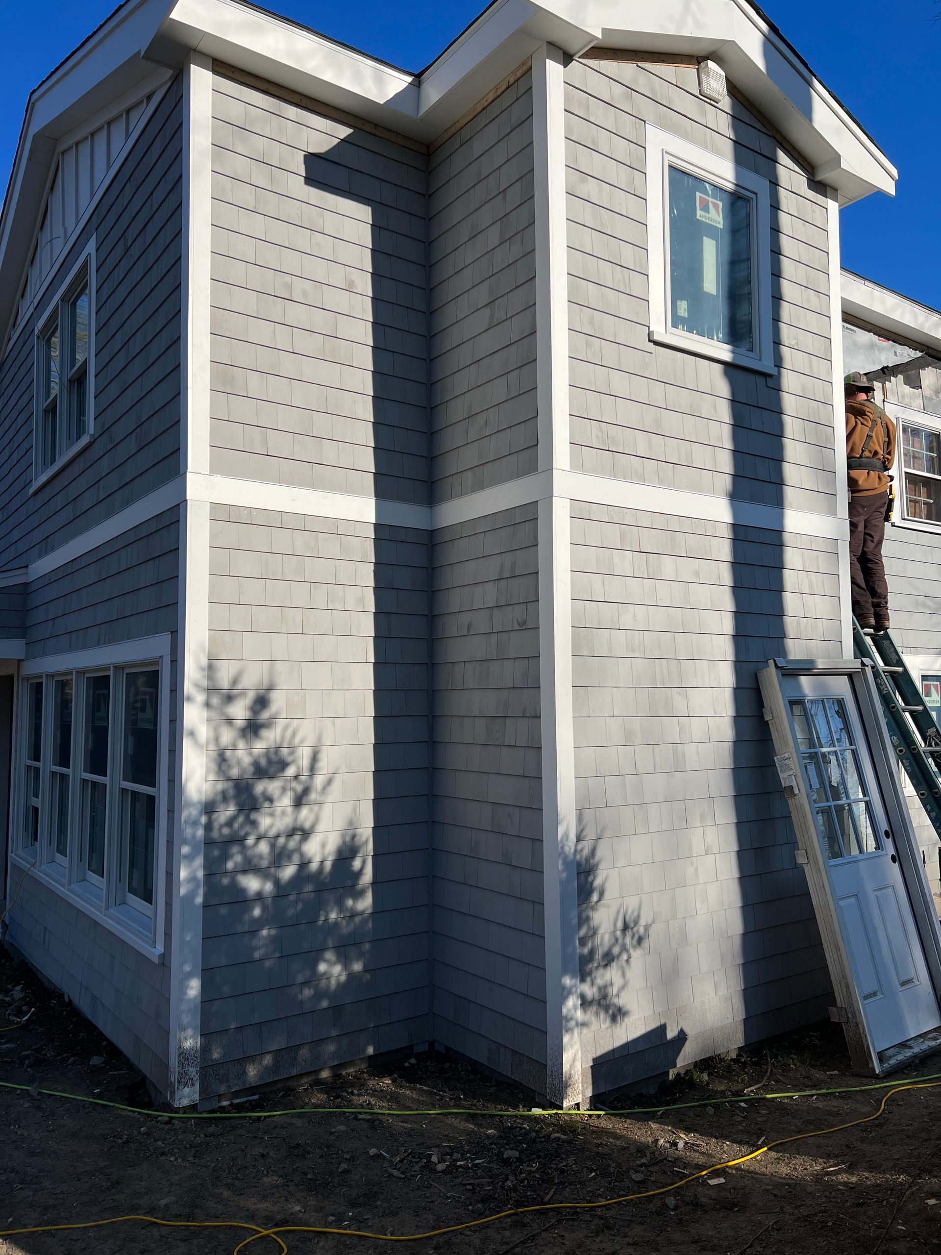 A man is standing on a ladder on the side of a house