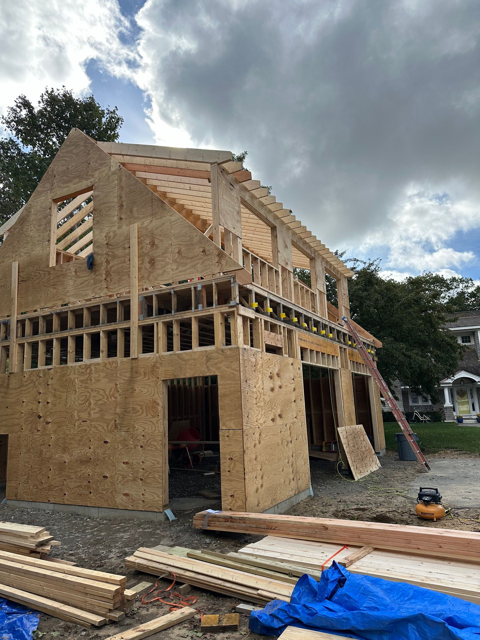 A house is being built with a blue tarp on the ground.