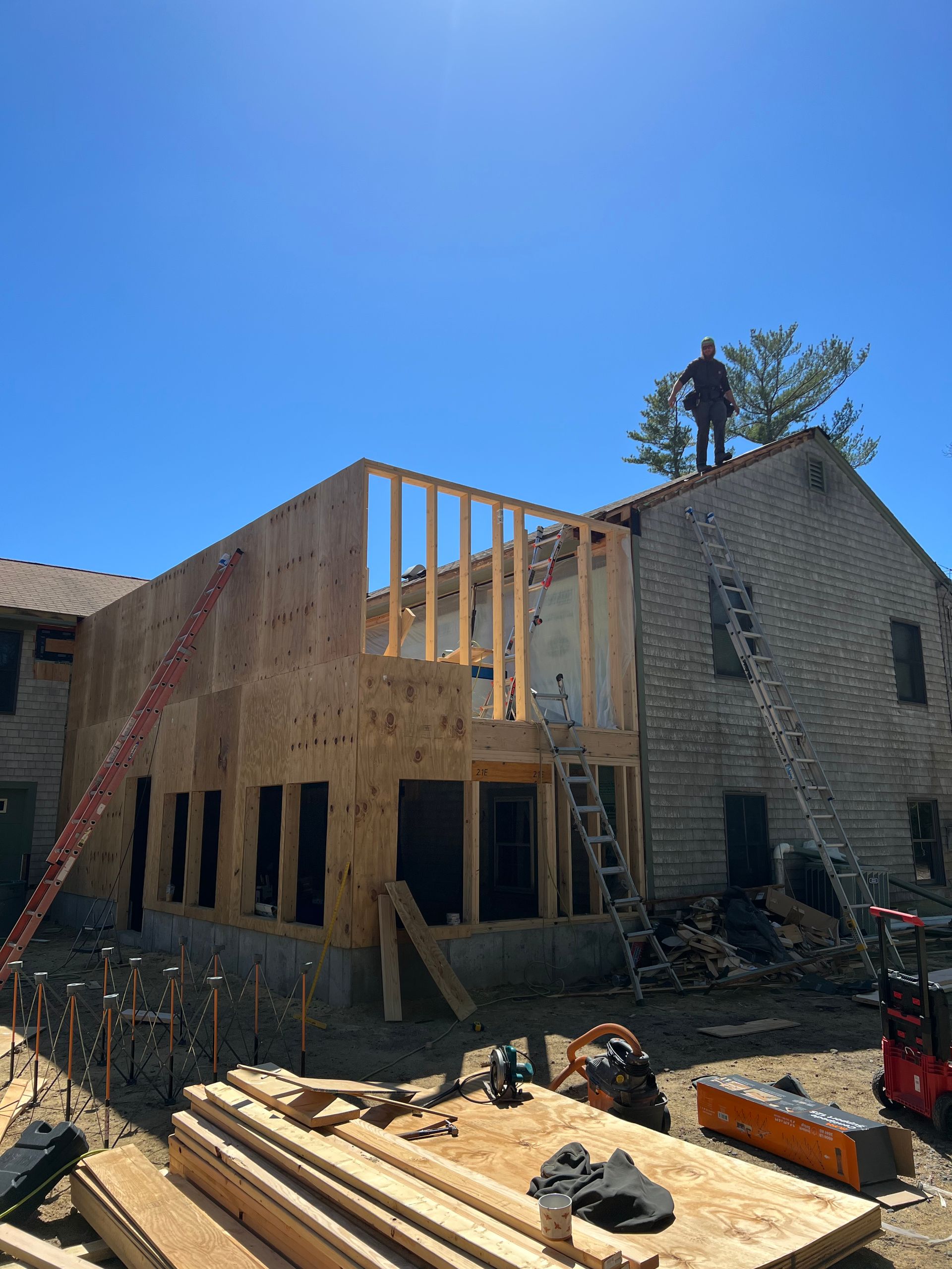 A man is standing on the roof of a house under construction.