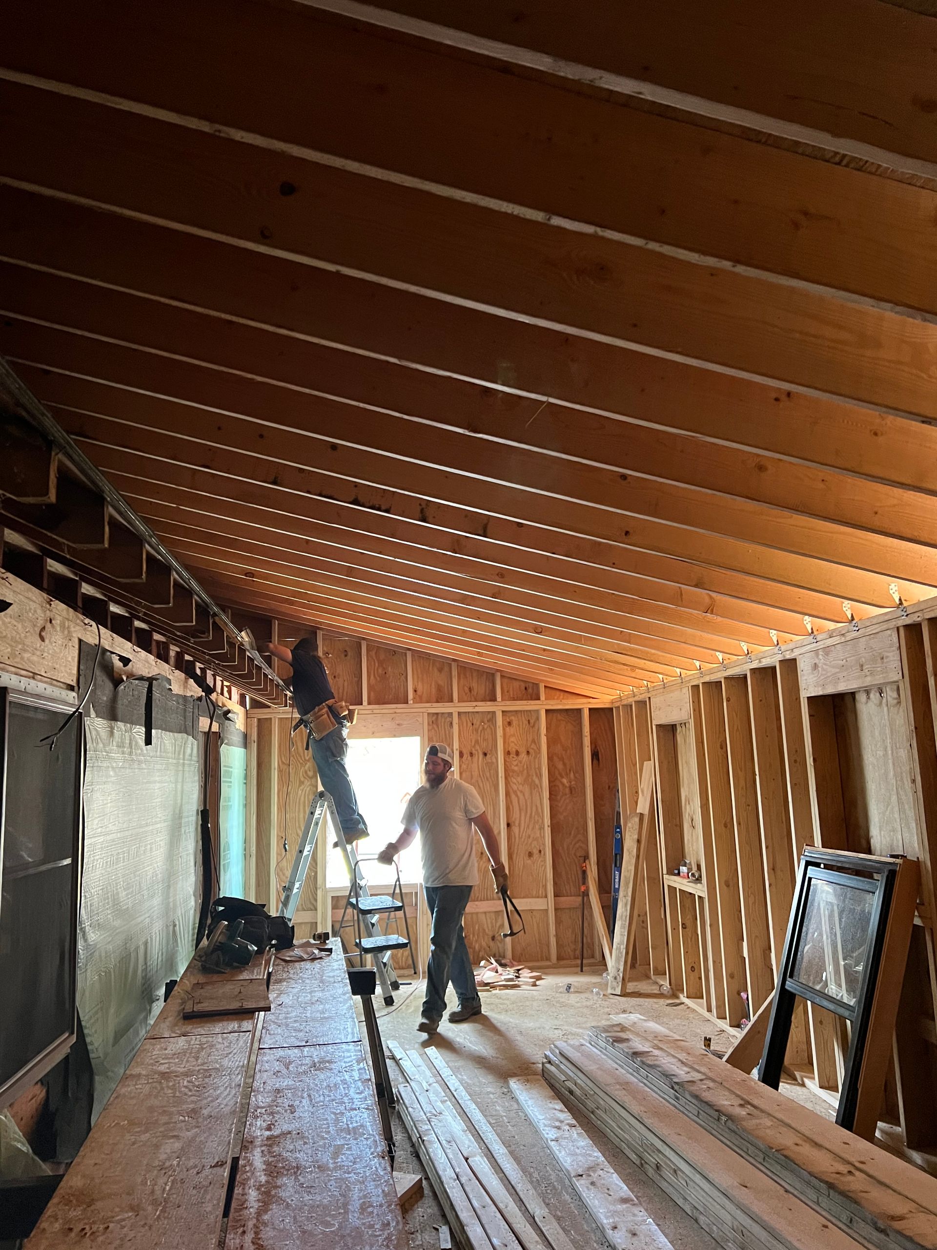 Two men are working on the ceiling of a building.