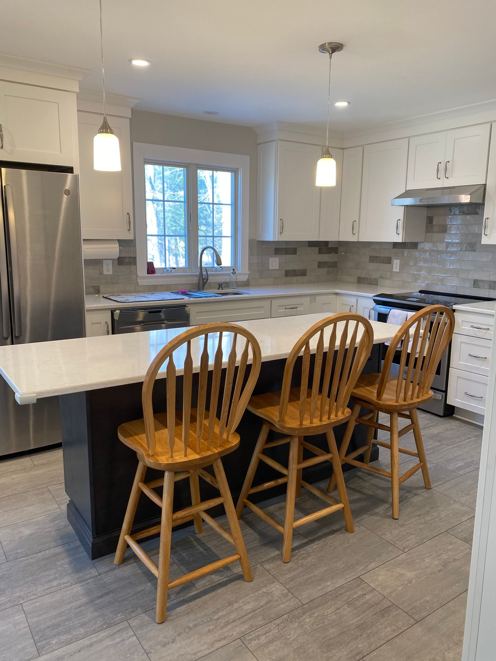 A kitchen with stainless steel appliances and wooden chairs