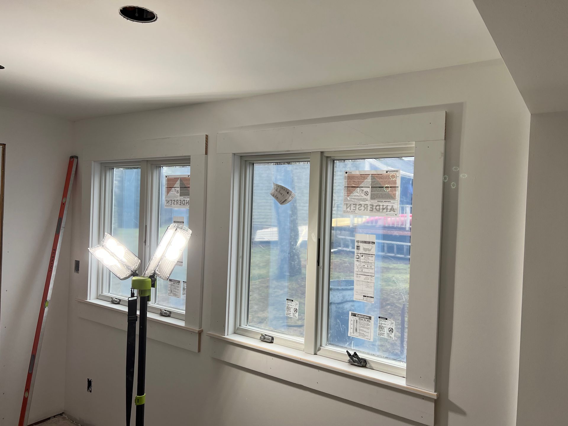 A room with three windows and a lamp on the floor.