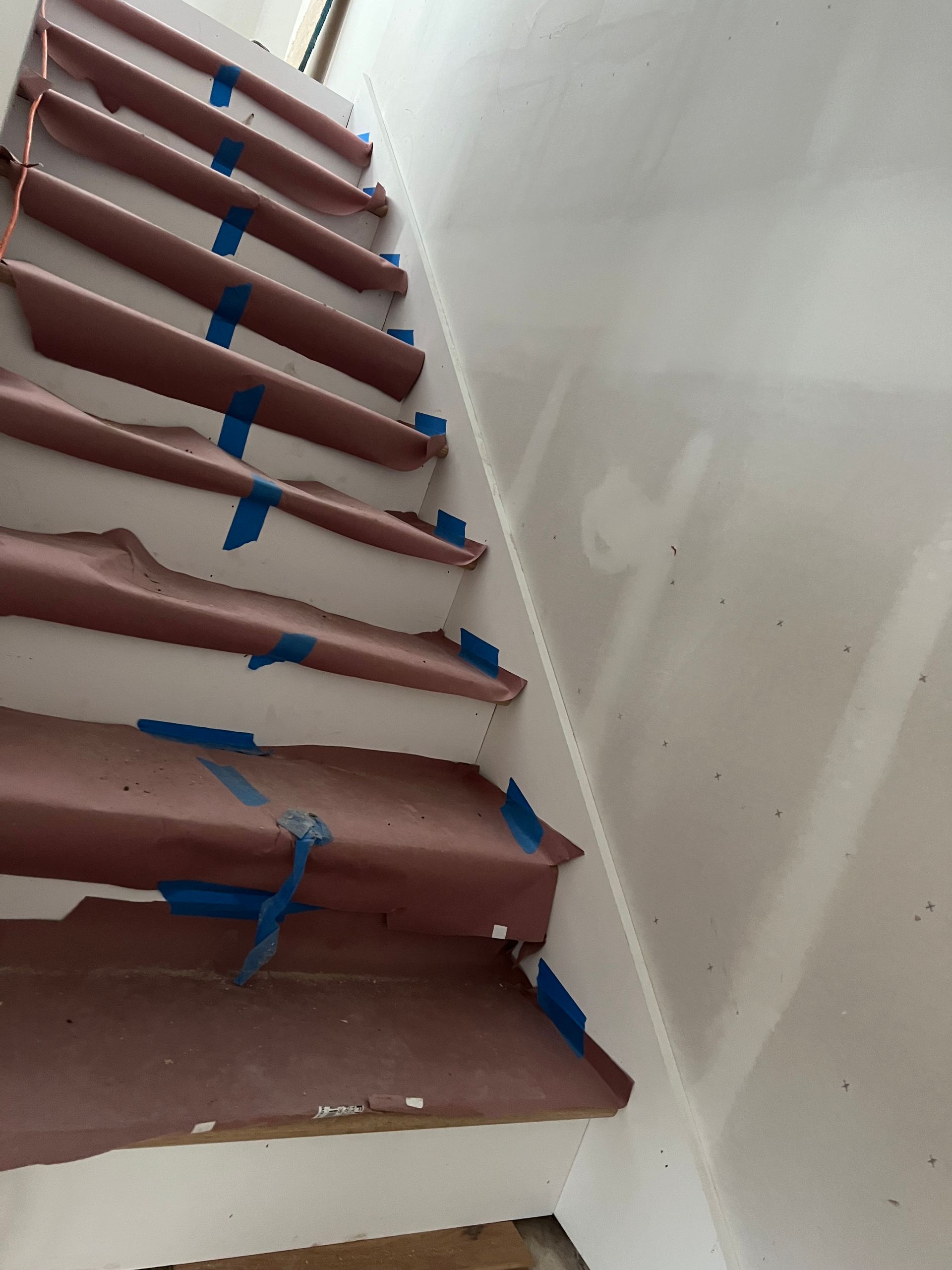 A set of stairs covered in brown paper and blue tape.