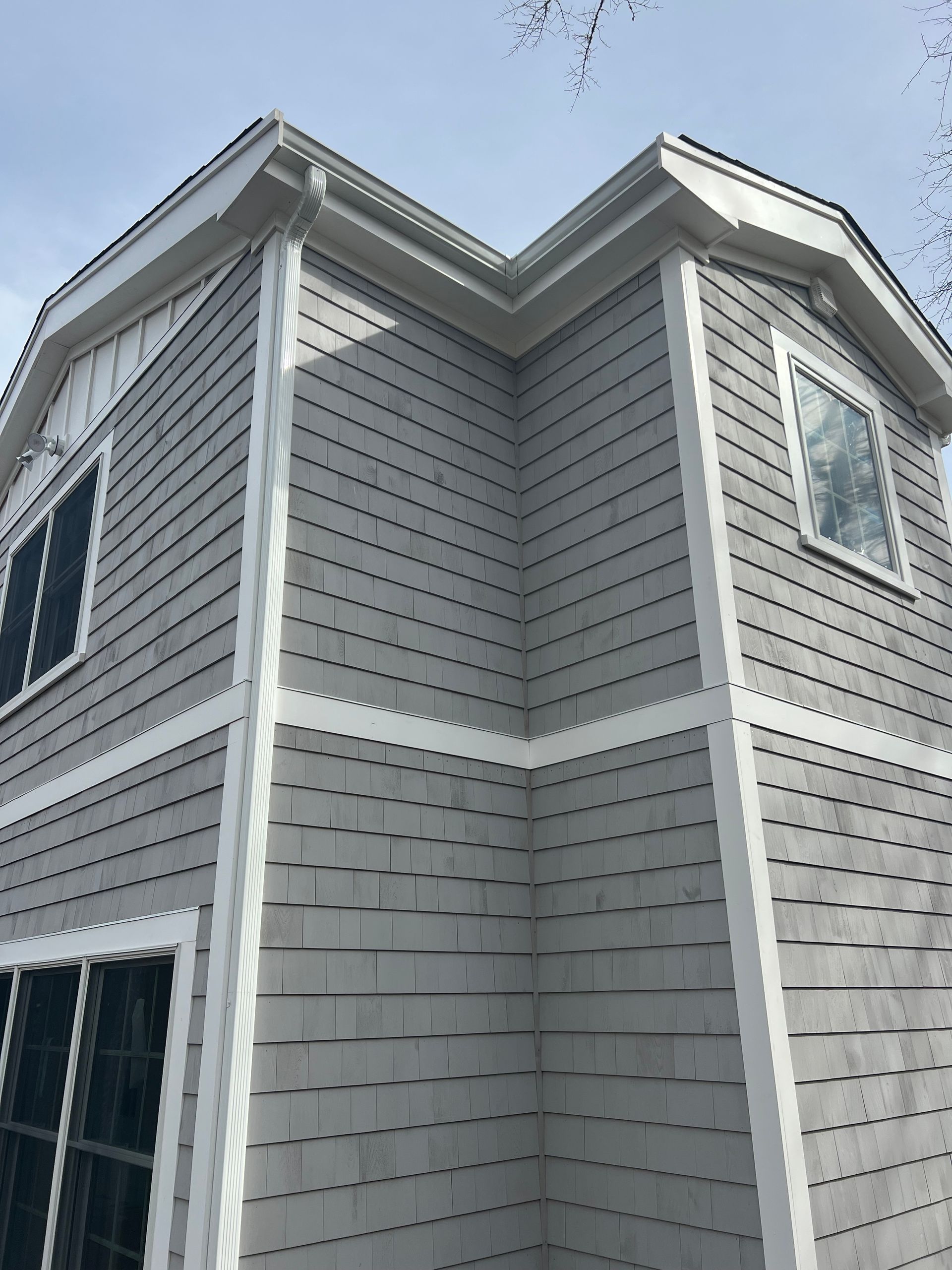 The corner of a house with a gray siding and white trim.