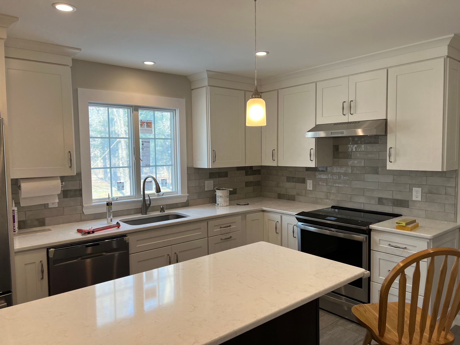 A kitchen with white cabinets , stainless steel appliances and a large island.