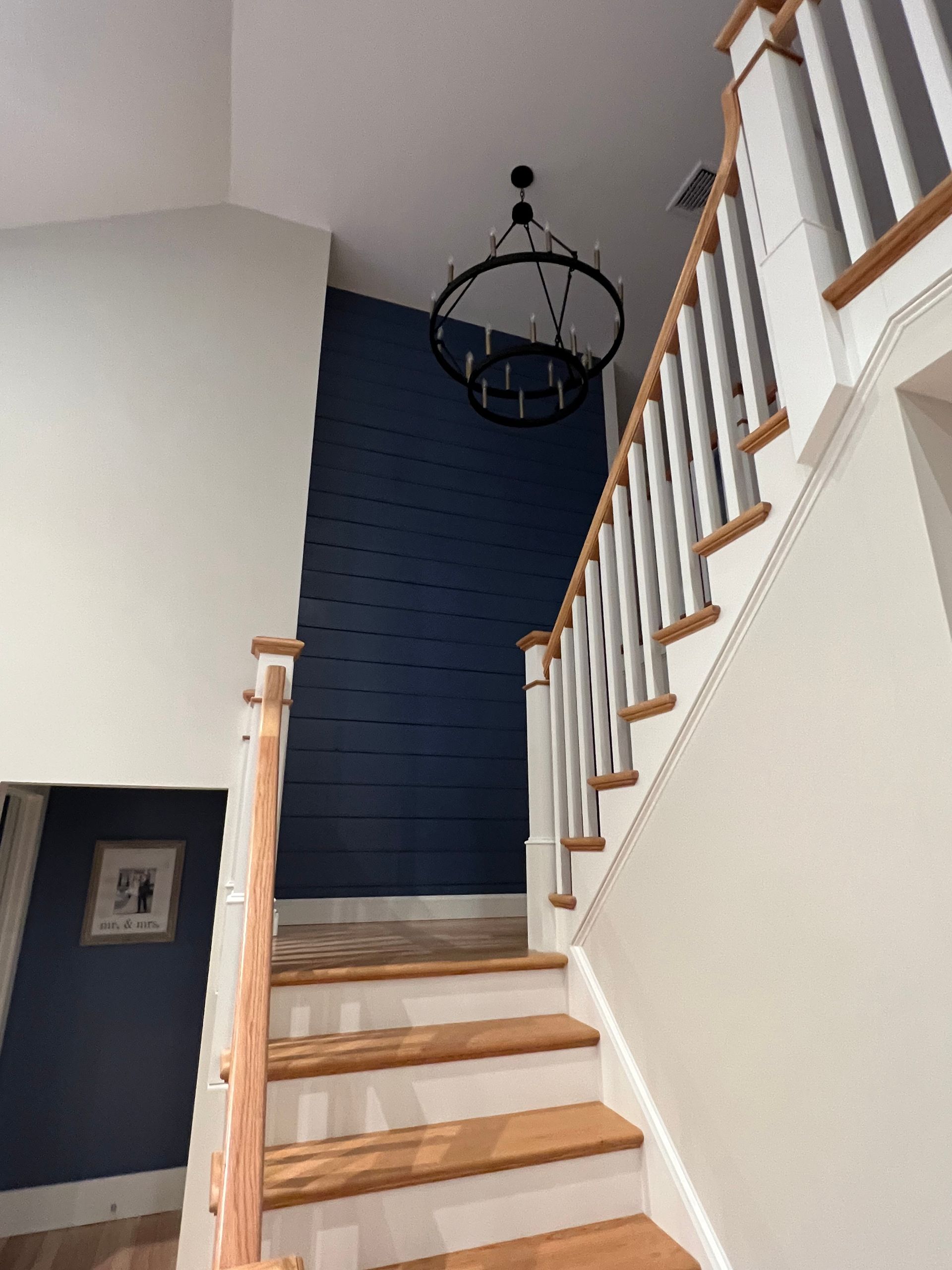 A staircase with a white railing and a chandelier hanging from the ceiling