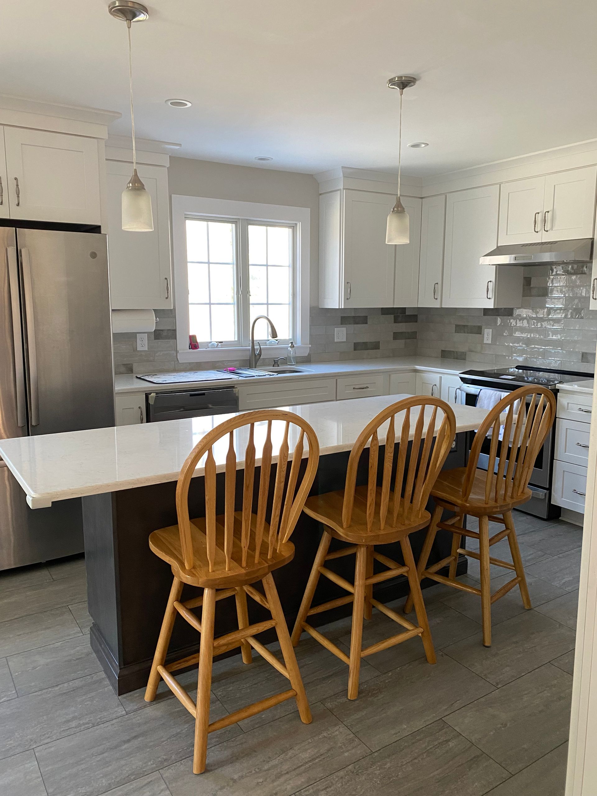 A kitchen with a large island and wooden chairs