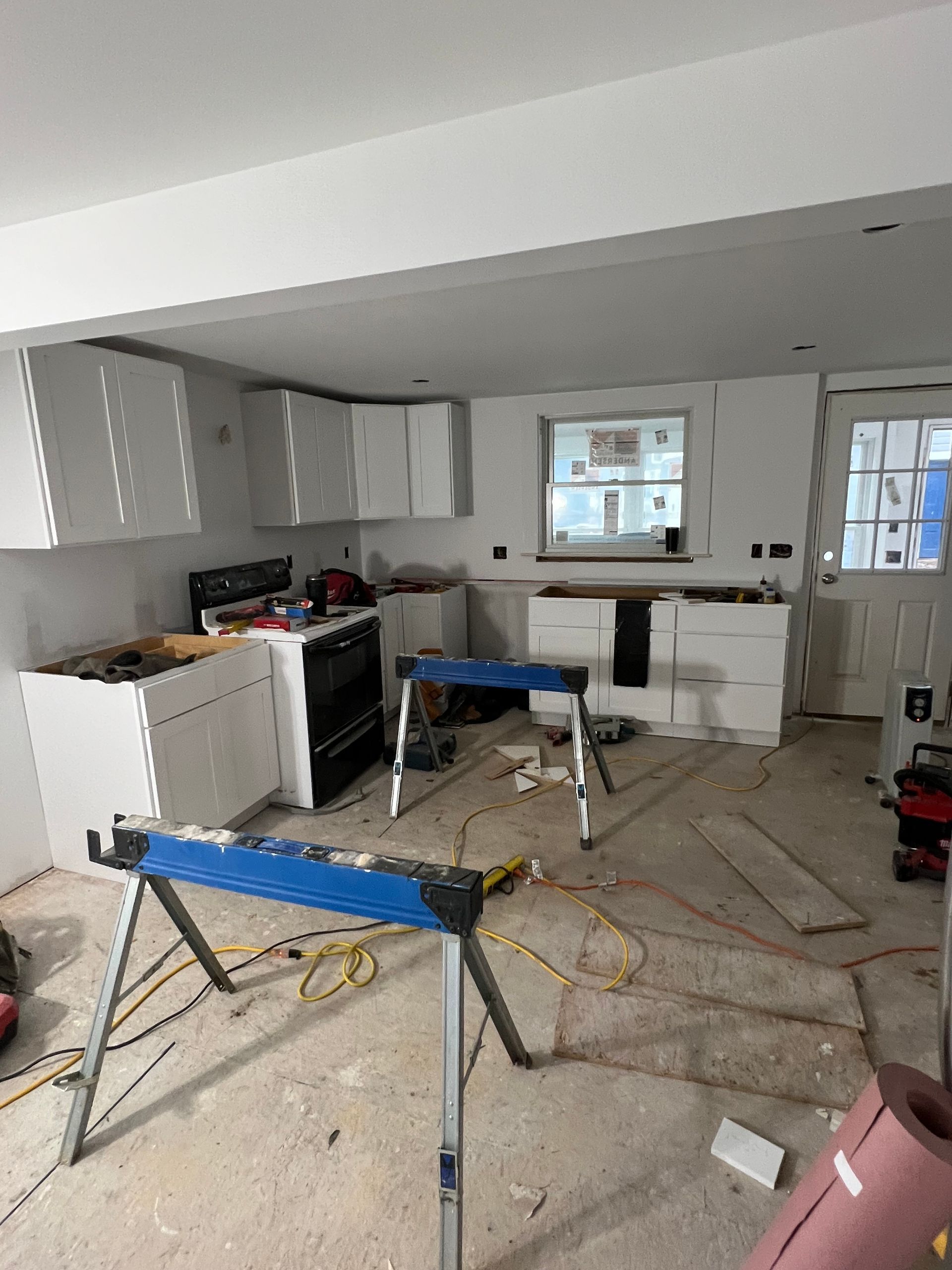 A kitchen under construction with a stove and a window.