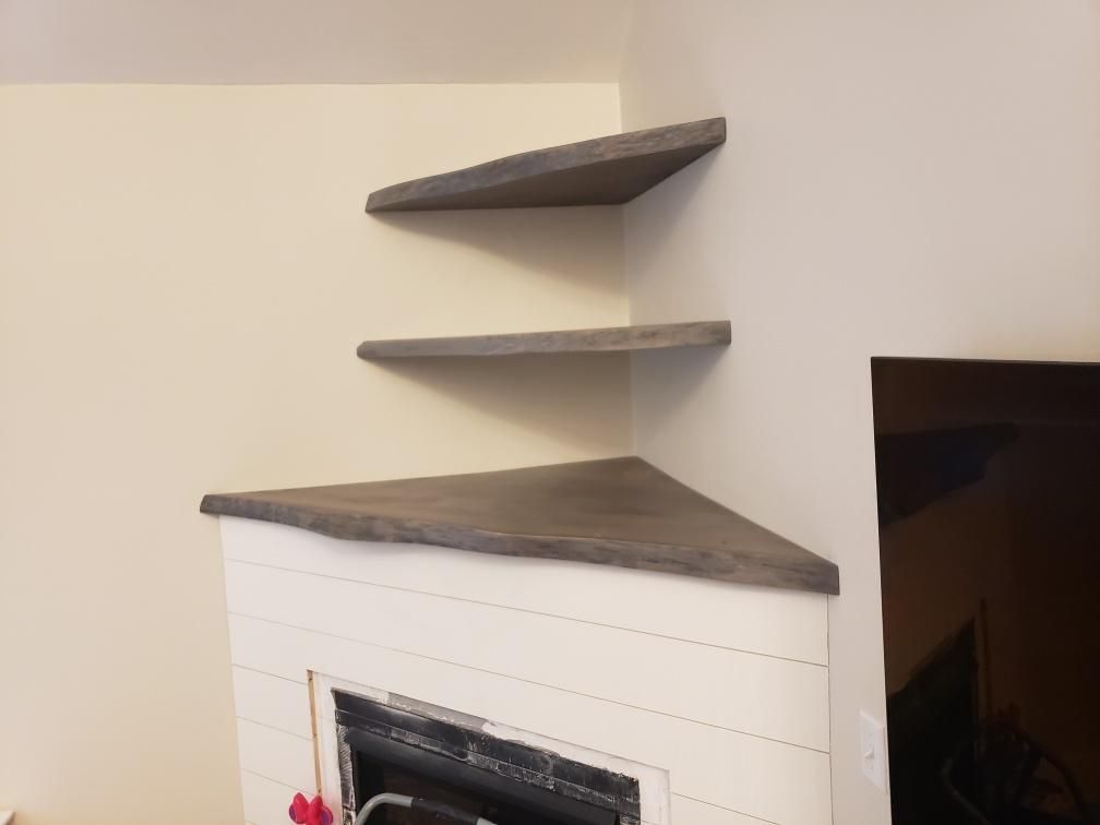 A fireplace with three shelves on the corner of it