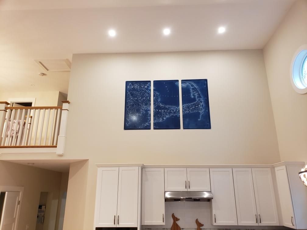 A kitchen with three paintings on the wall above the stove
