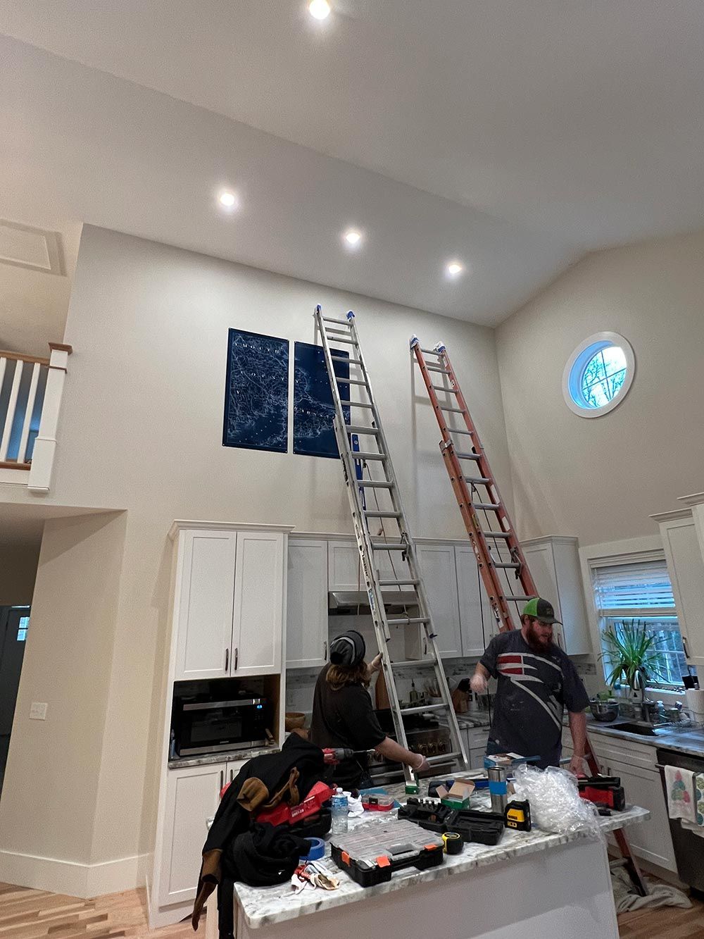 A group of people are working in a kitchen with ladders.
