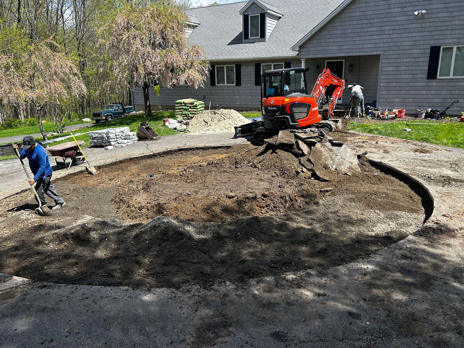 A man is digging a hole in the dirt in front of a house.