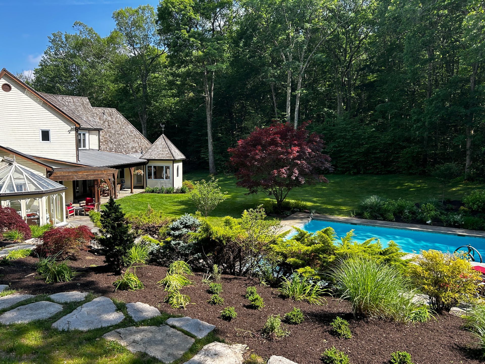 A large house with a swimming pool in the backyard surrounded by trees.