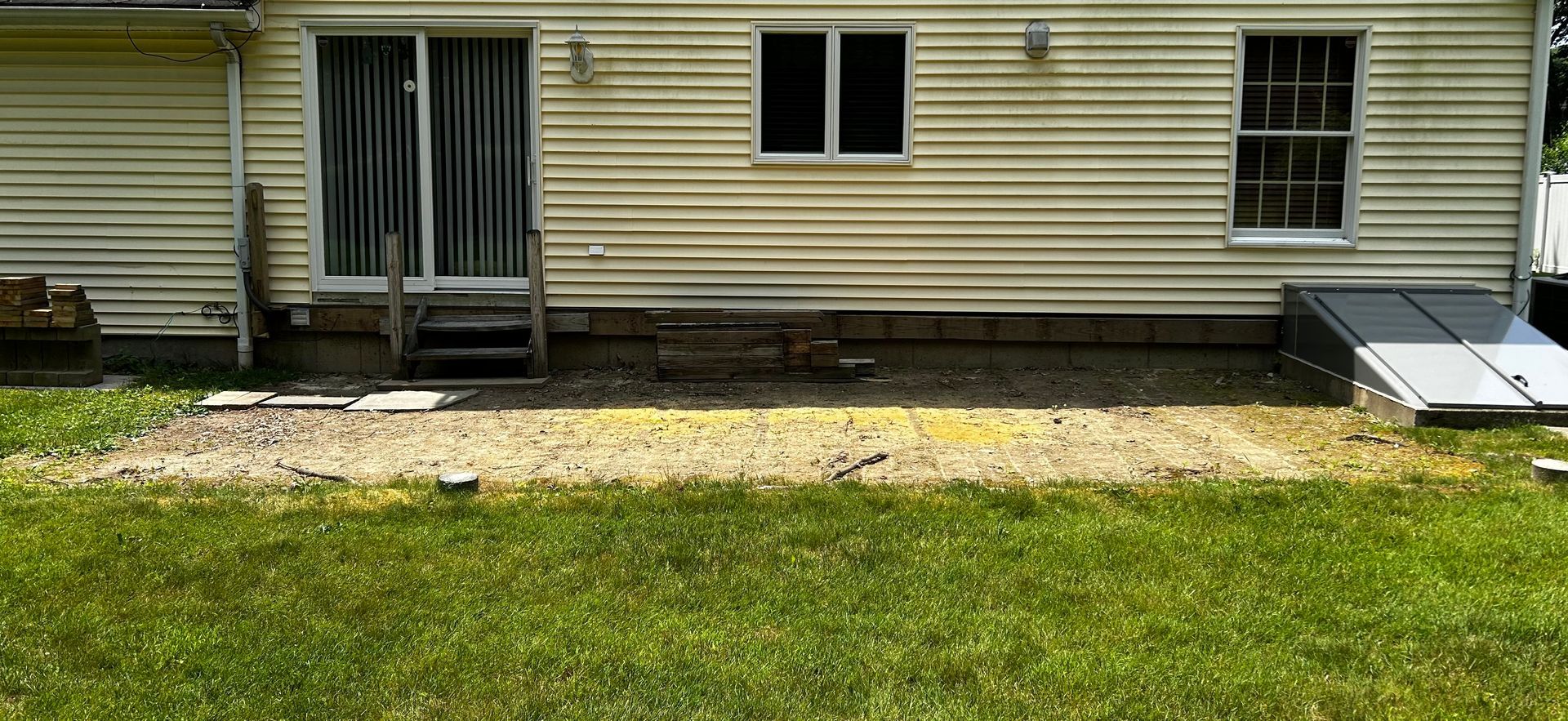 The back of a house with a patio in front of it.