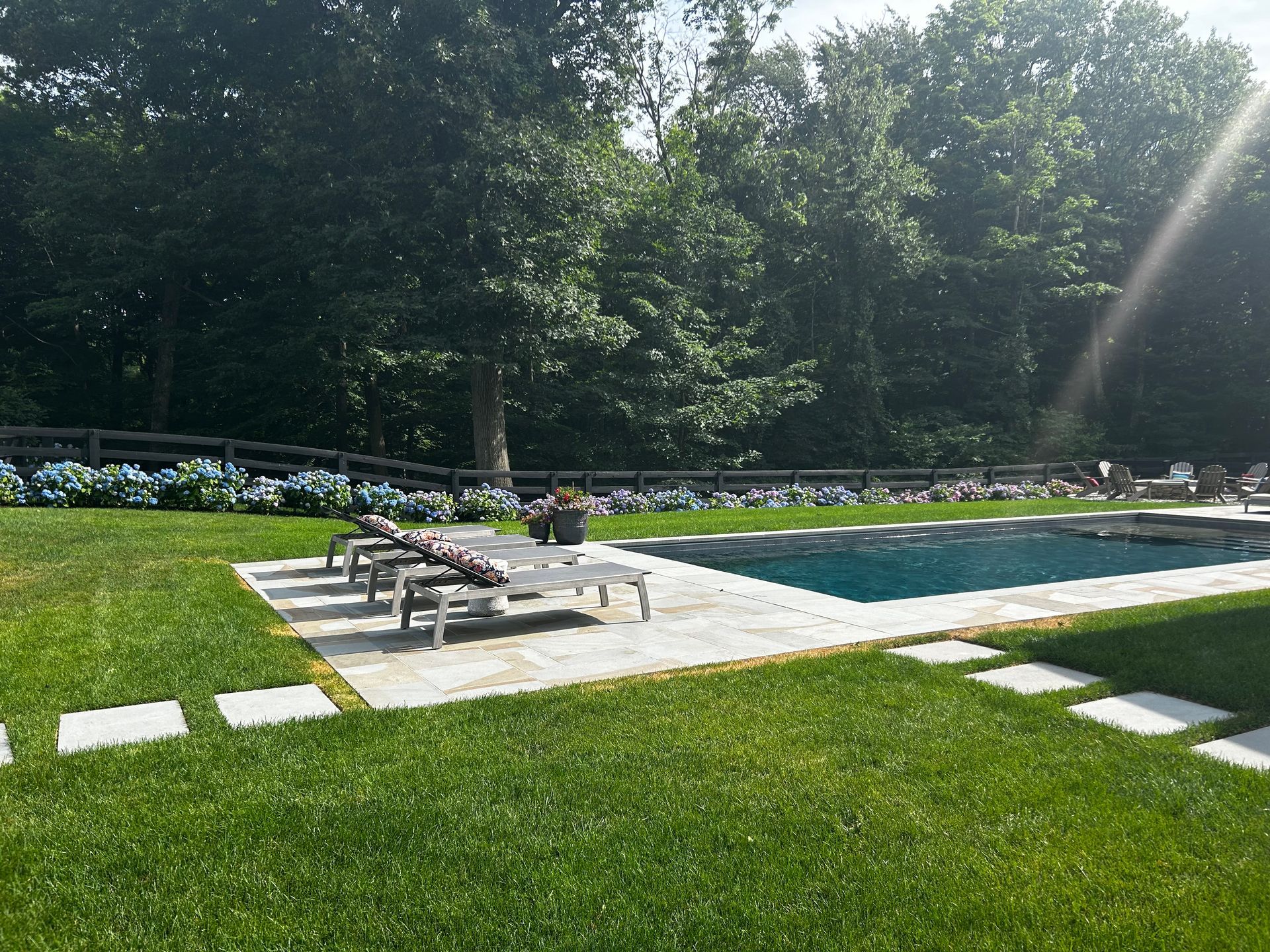 A large swimming pool is surrounded by a lush green lawn