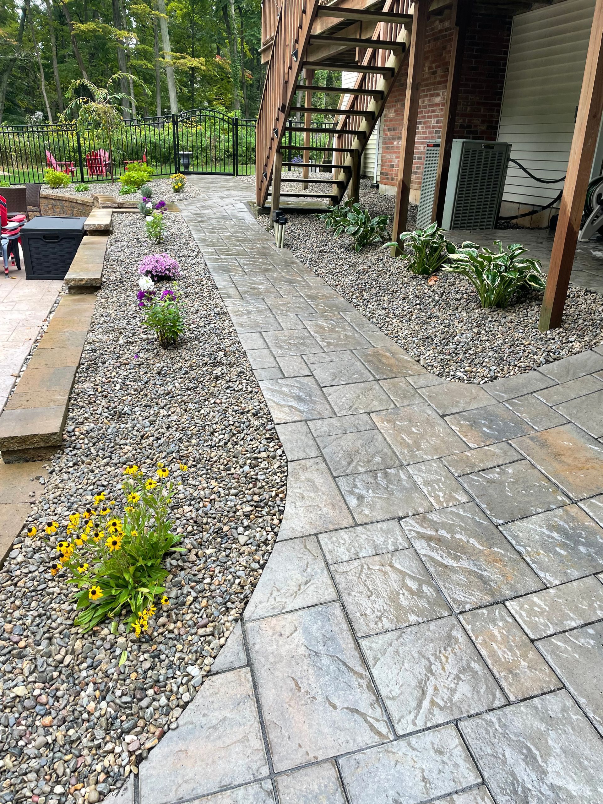 A stone walkway leading to a staircase in a backyard.