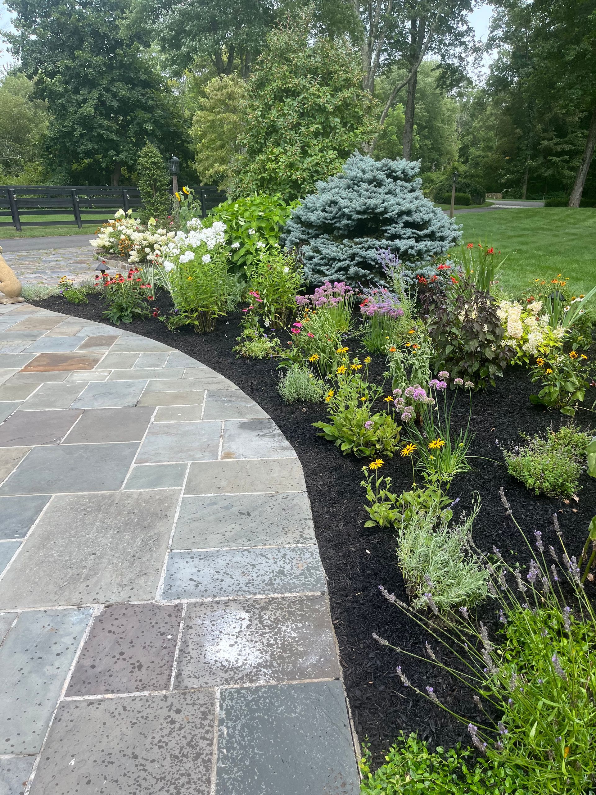 A stone walkway with flowers on the side of it