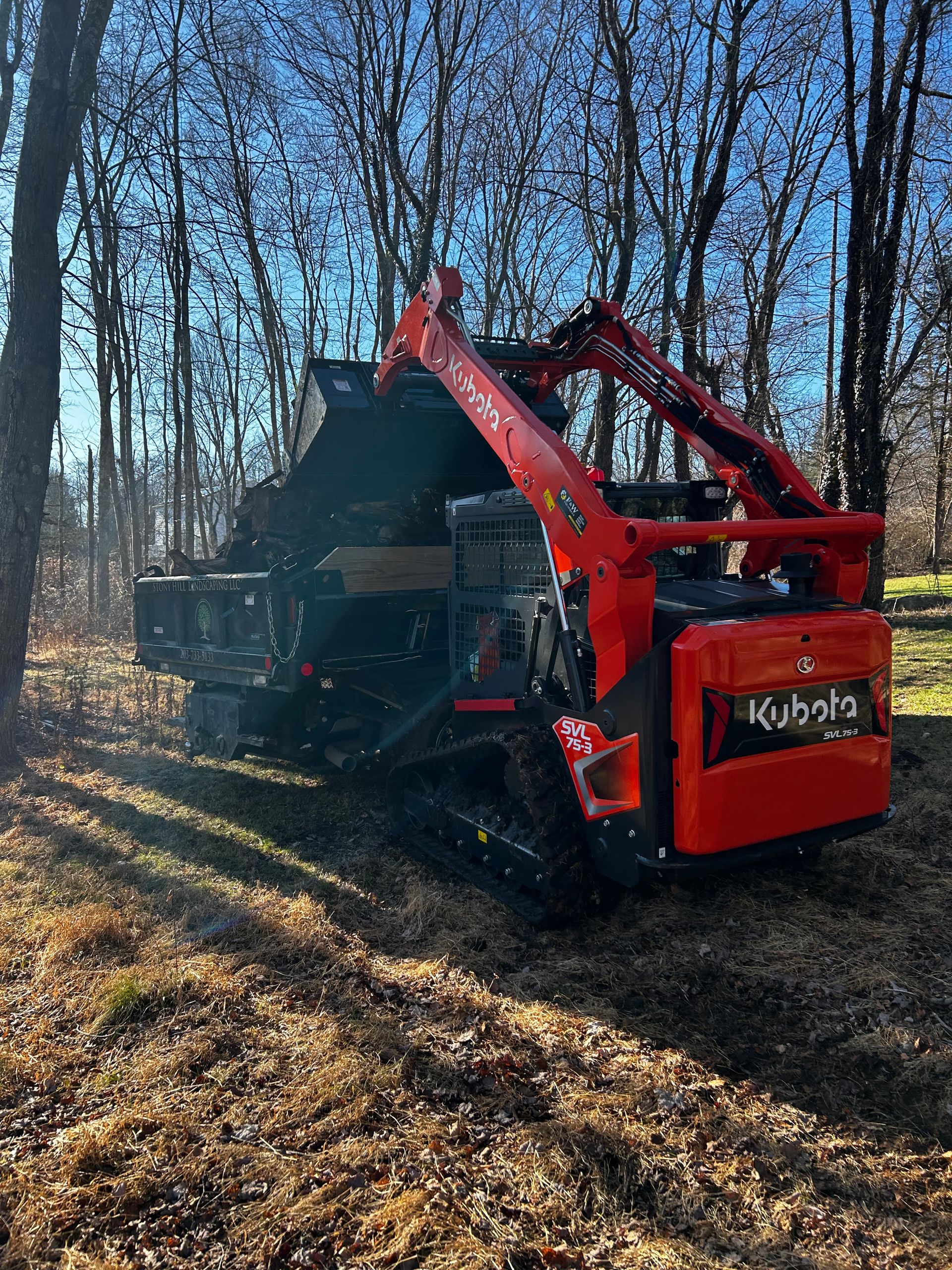 A red tractor is sitting in the middle of a forest.