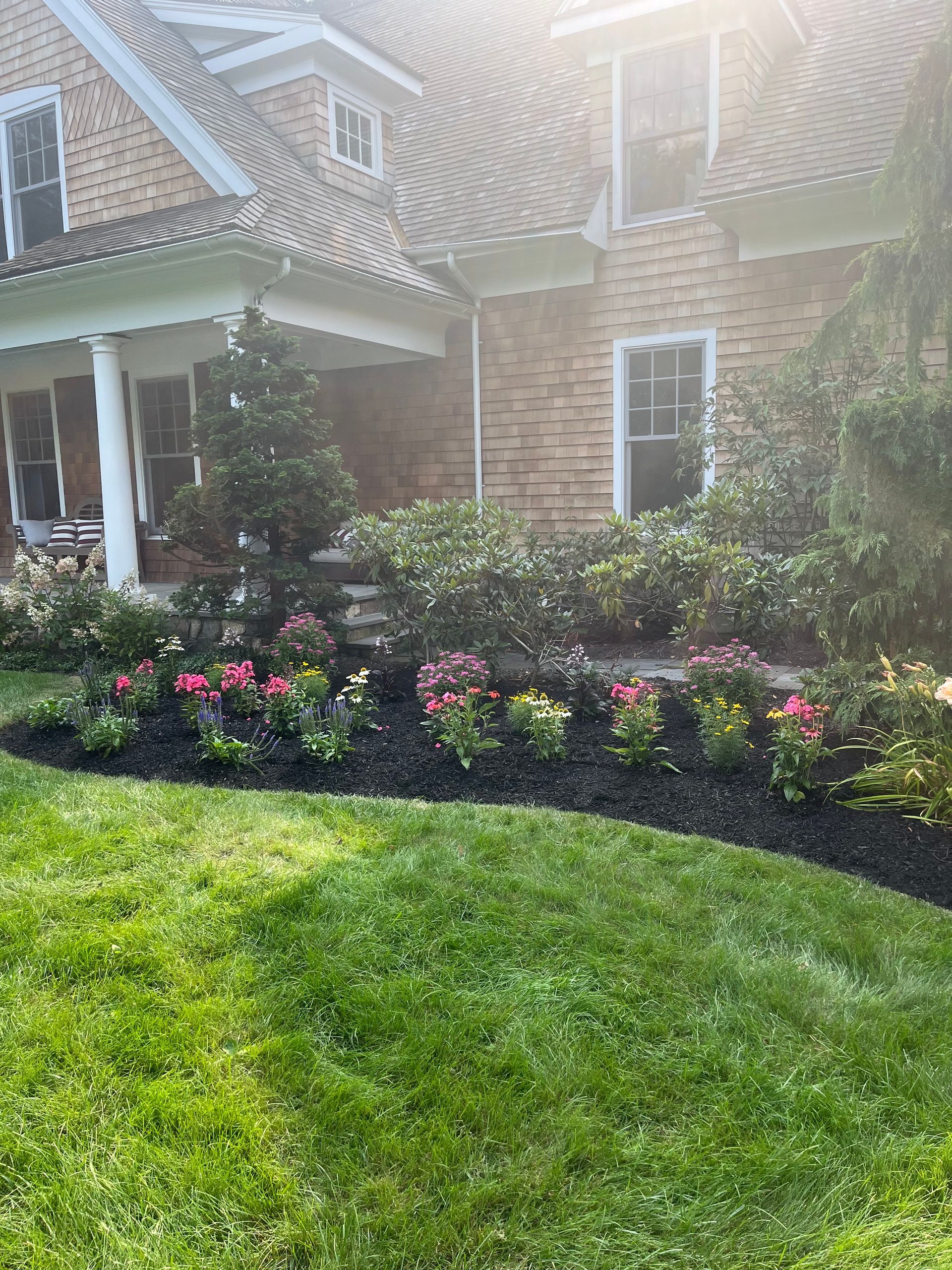 A large brick house with a lush green lawn and flowers in front of it.