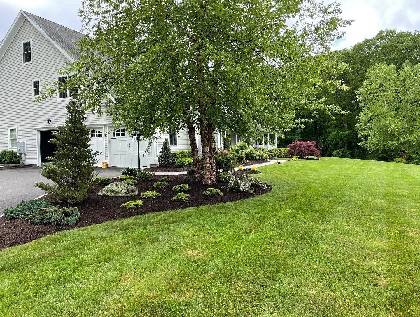 A white house with a large lush green lawn in front of it.