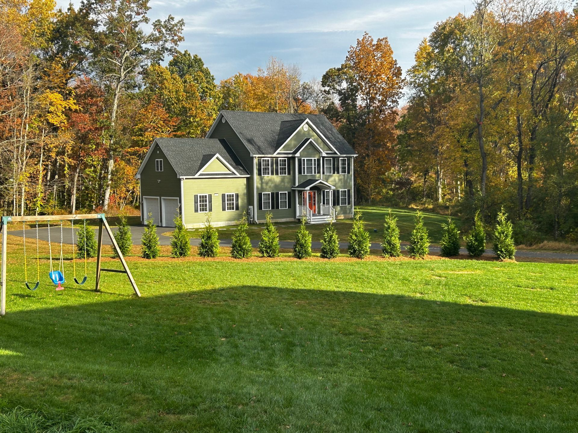 A large house with a swing set in front of it