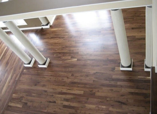 Dark wood flooring with white support columns and overhead beams.