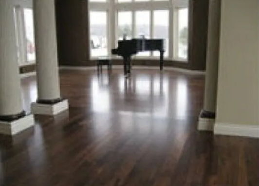 Spacious room with shiny hardwood floor, pillars, grand piano near large windows.