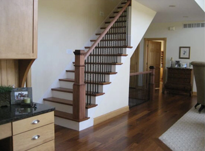 Wooden staircase with dark spindles and hardwood floor in a home.