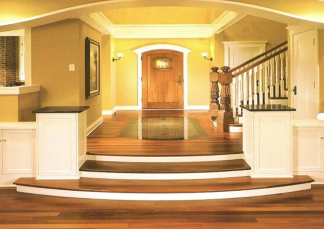Entryway with hardwood floors, a curved staircase, and a wooden door. Yellow walls and white trim.