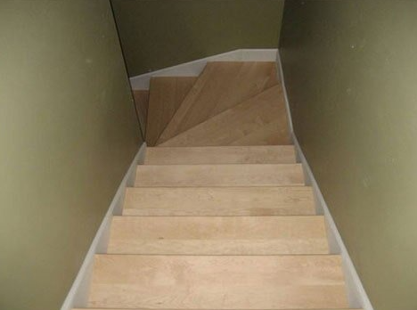 Staircase with light-colored wooden steps and white trim, leading downwards between olive green walls.