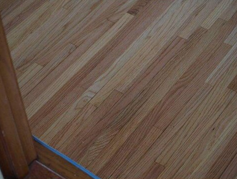 Wooden hardwood floor, planks in diagonal pattern, brown tones.