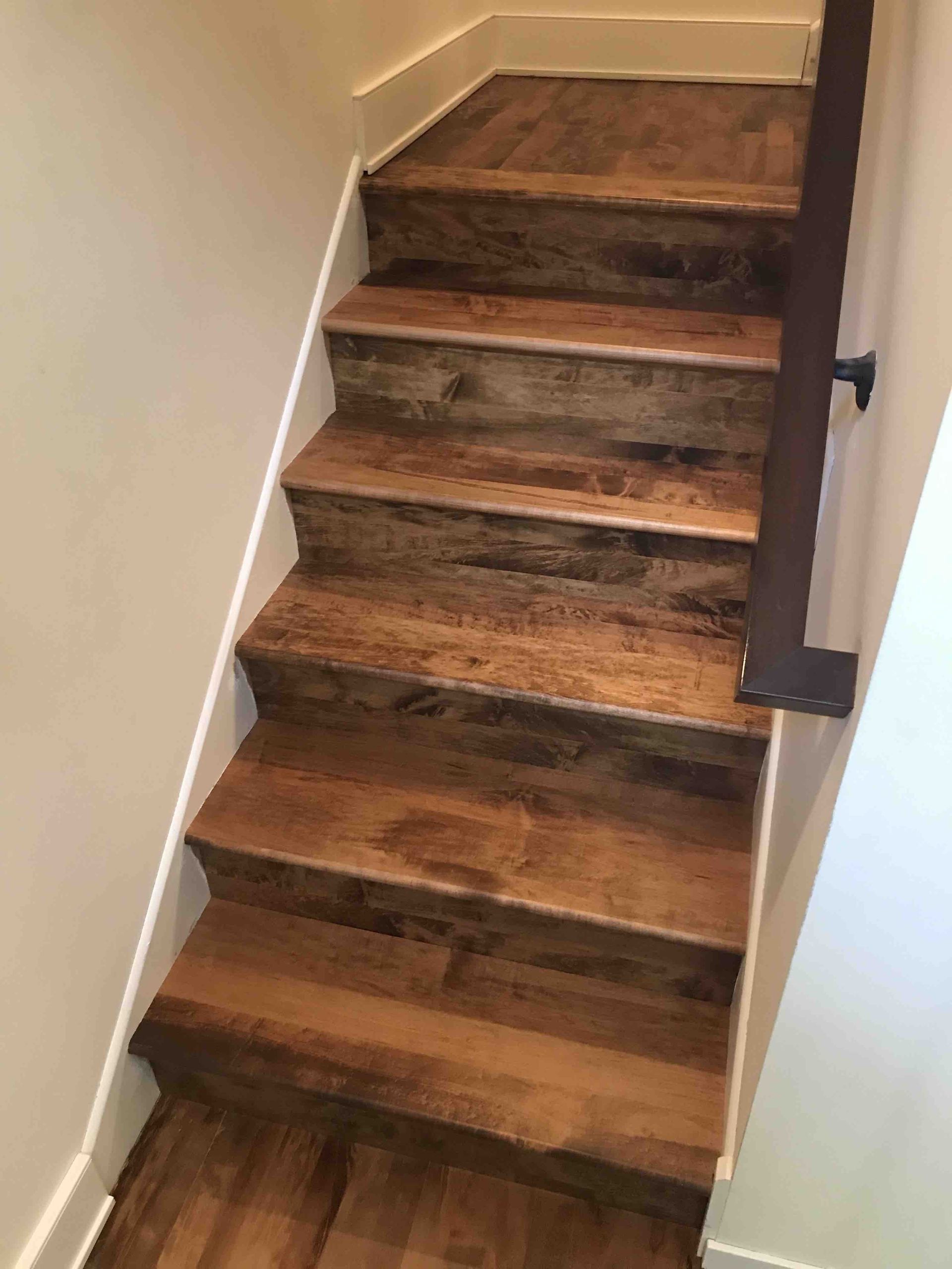 Wooden staircase with dark metal spindles and a wooden handrail.