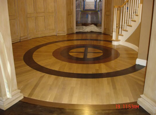 Circular hardwood floor with dark and light wood concentric rings, entryway.