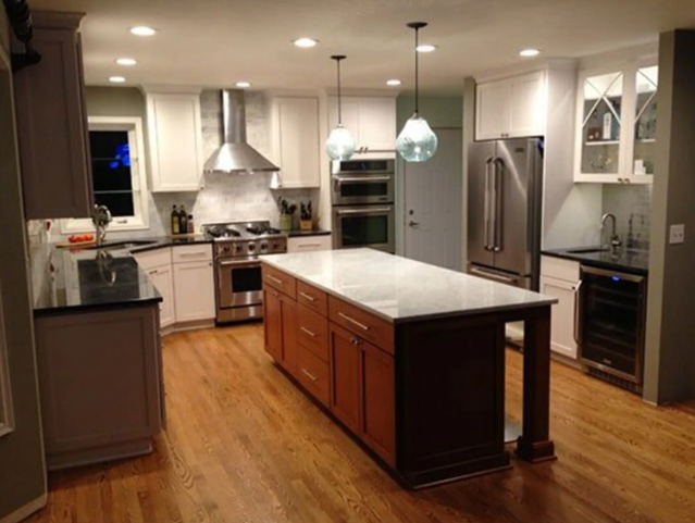 Kitchen with white and brown cabinets, stainless steel appliances, island with granite countertop.