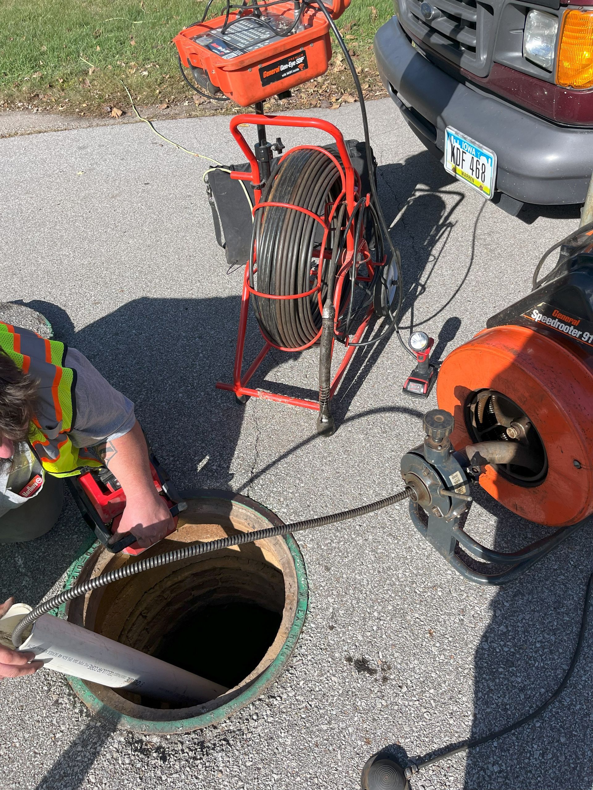 A man is looking into a manhole next to a truck.