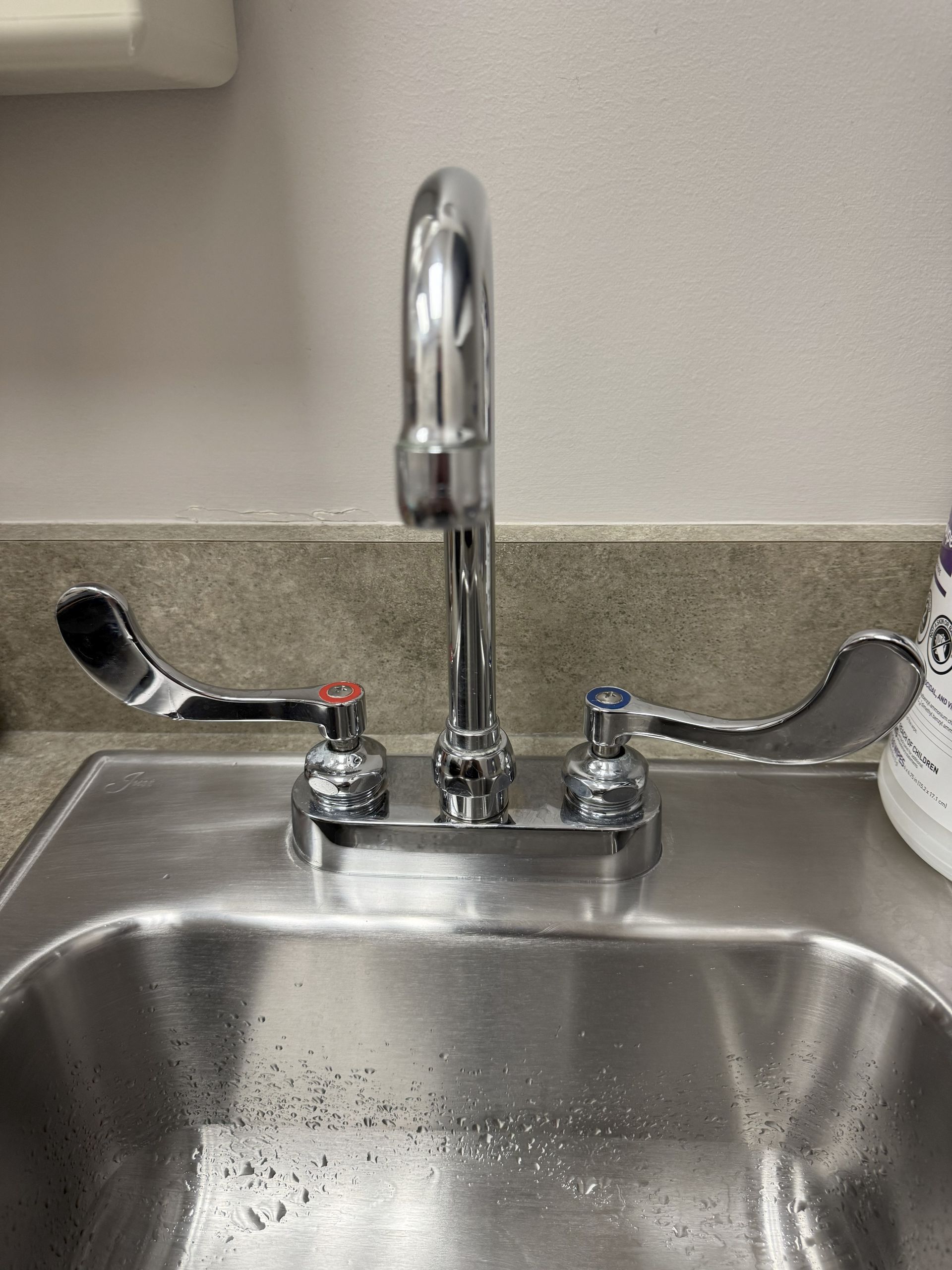 A stainless steel sink with a chrome faucet on a counter.