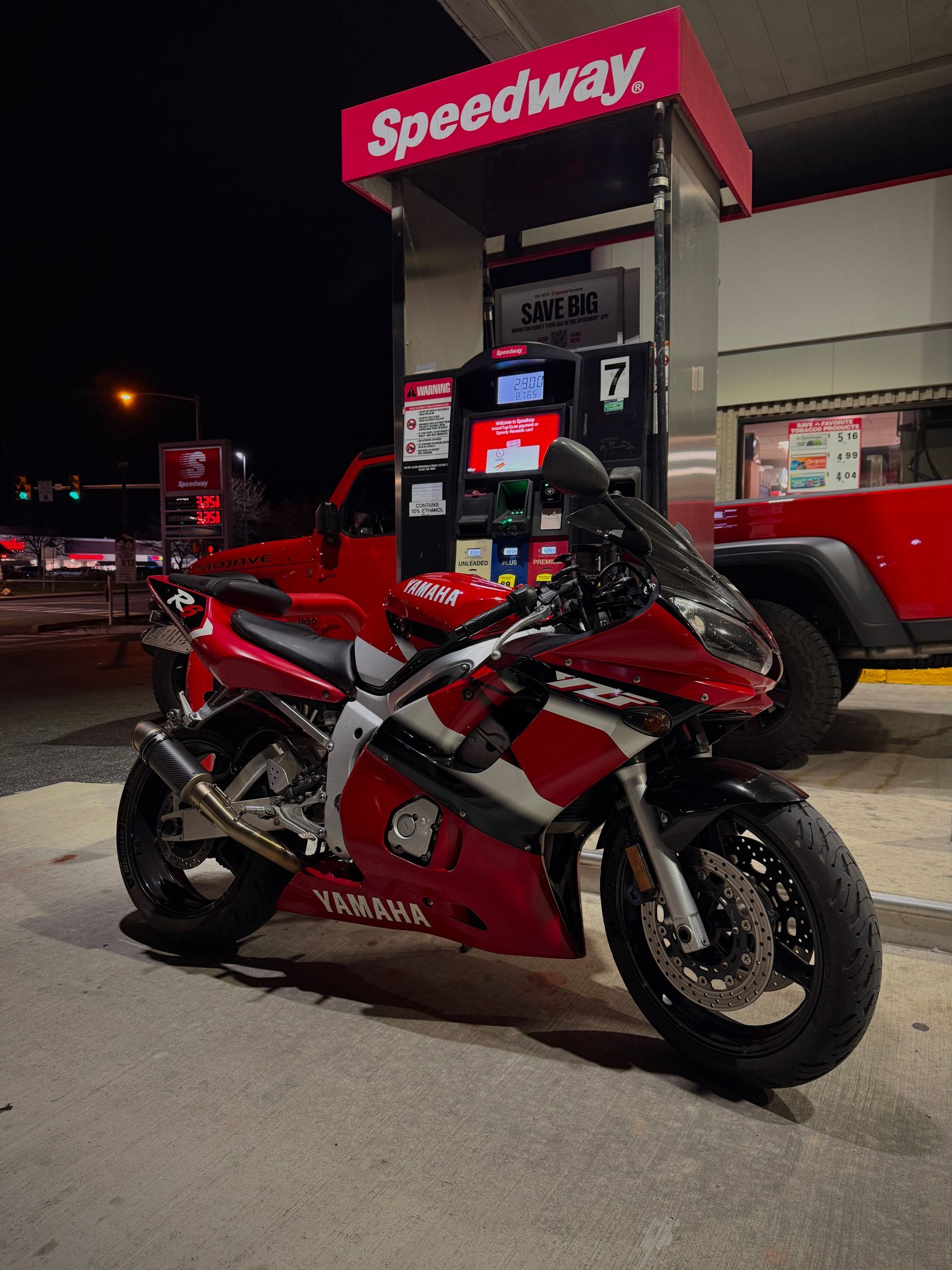 Red and black Yamaha sportbike at a Speedway gas pump at night.