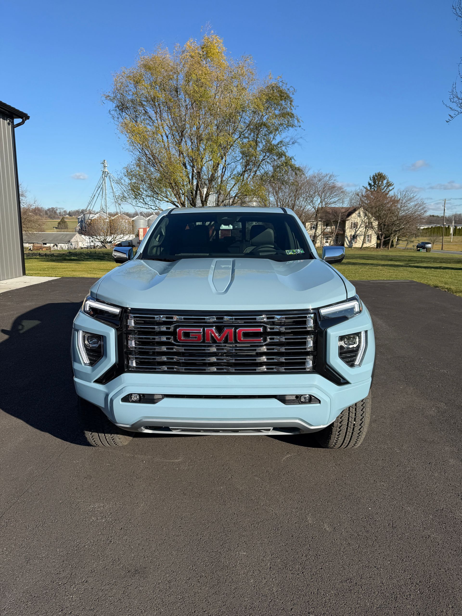 Light blue GMC truck parked in front of a building on a sunny day.