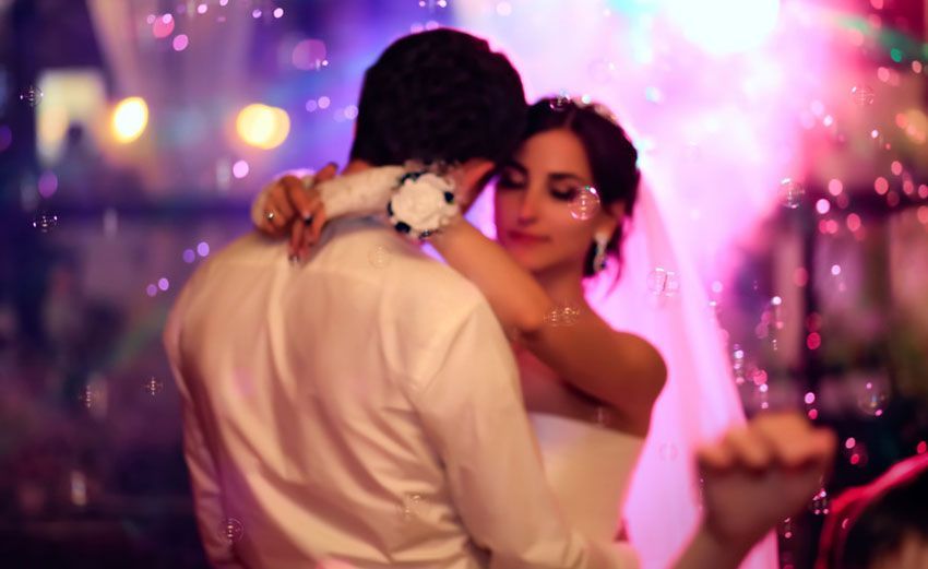 A bride and groom are dancing their first dance at their wedding reception.