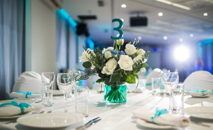 A table set for a wedding reception with a vase of flowers and a table number.