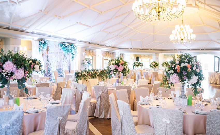 A large room with tables and chairs set up for a wedding reception.