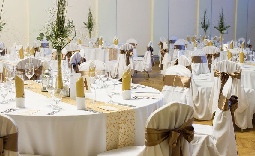 A large room with tables and chairs set up for a wedding reception.
