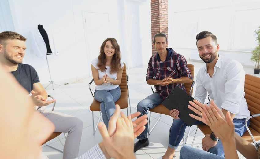 A group of people are sitting in a circle clapping their hands.