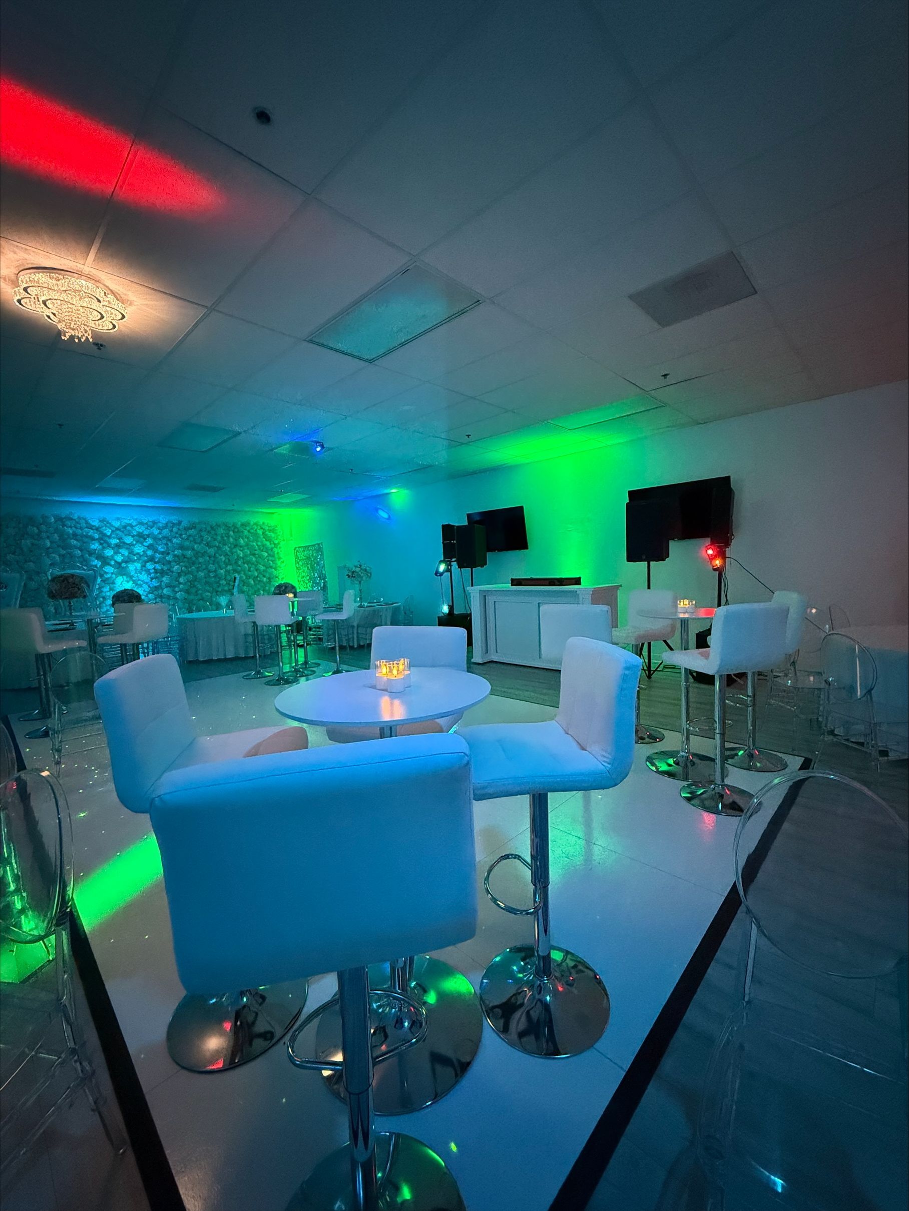 A room with tables and chairs and a television on the wall.