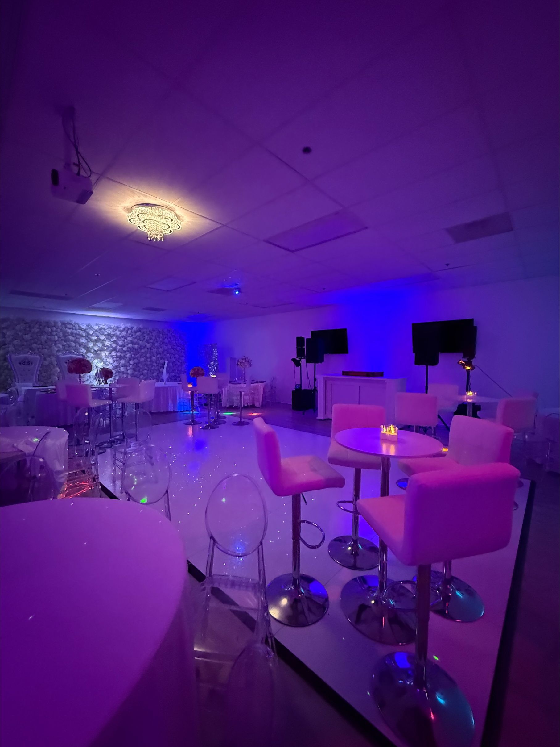 A large room with tables and chairs and purple lights.