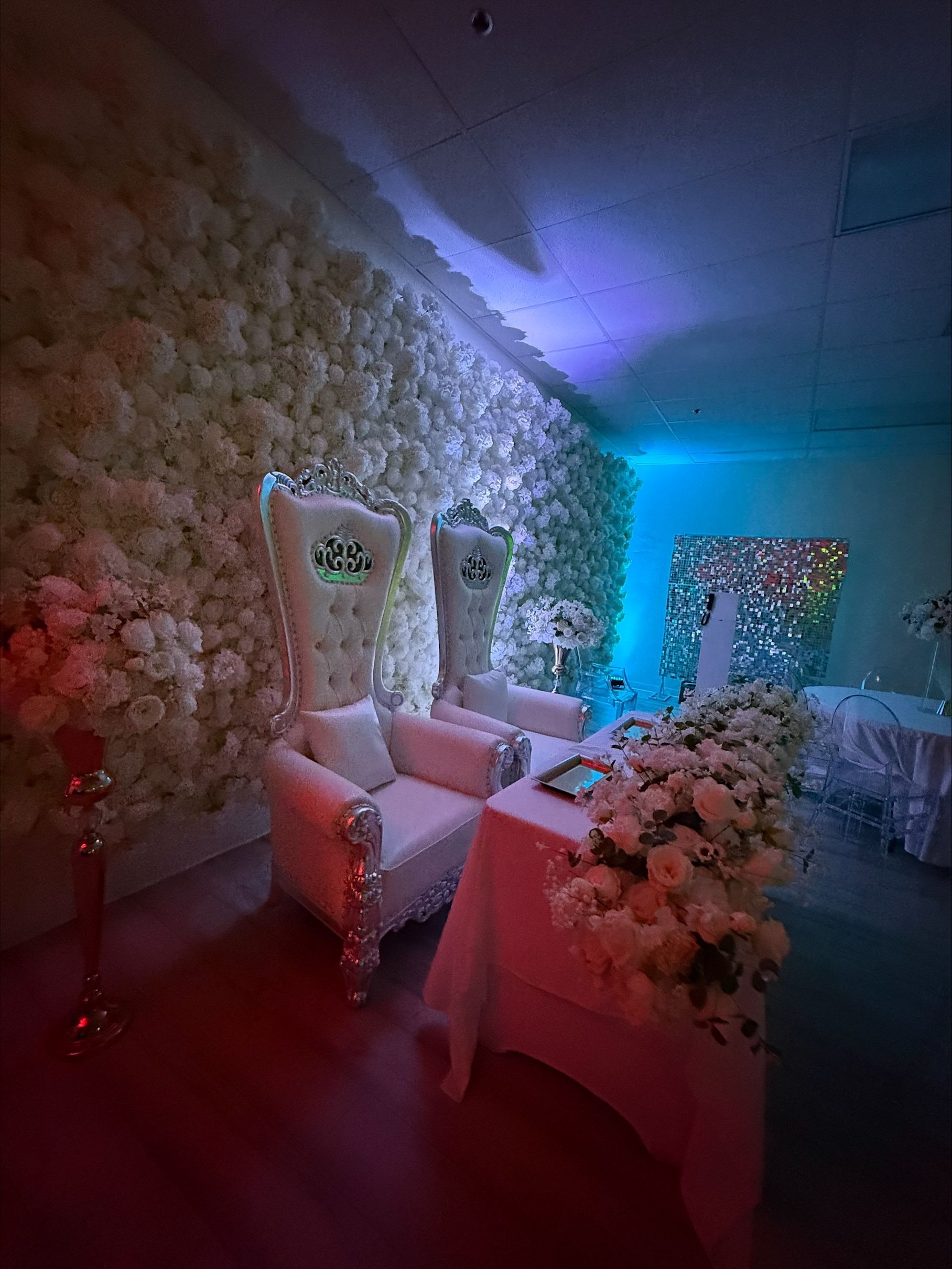 A couple of chairs sitting in front of a wall of flowers.